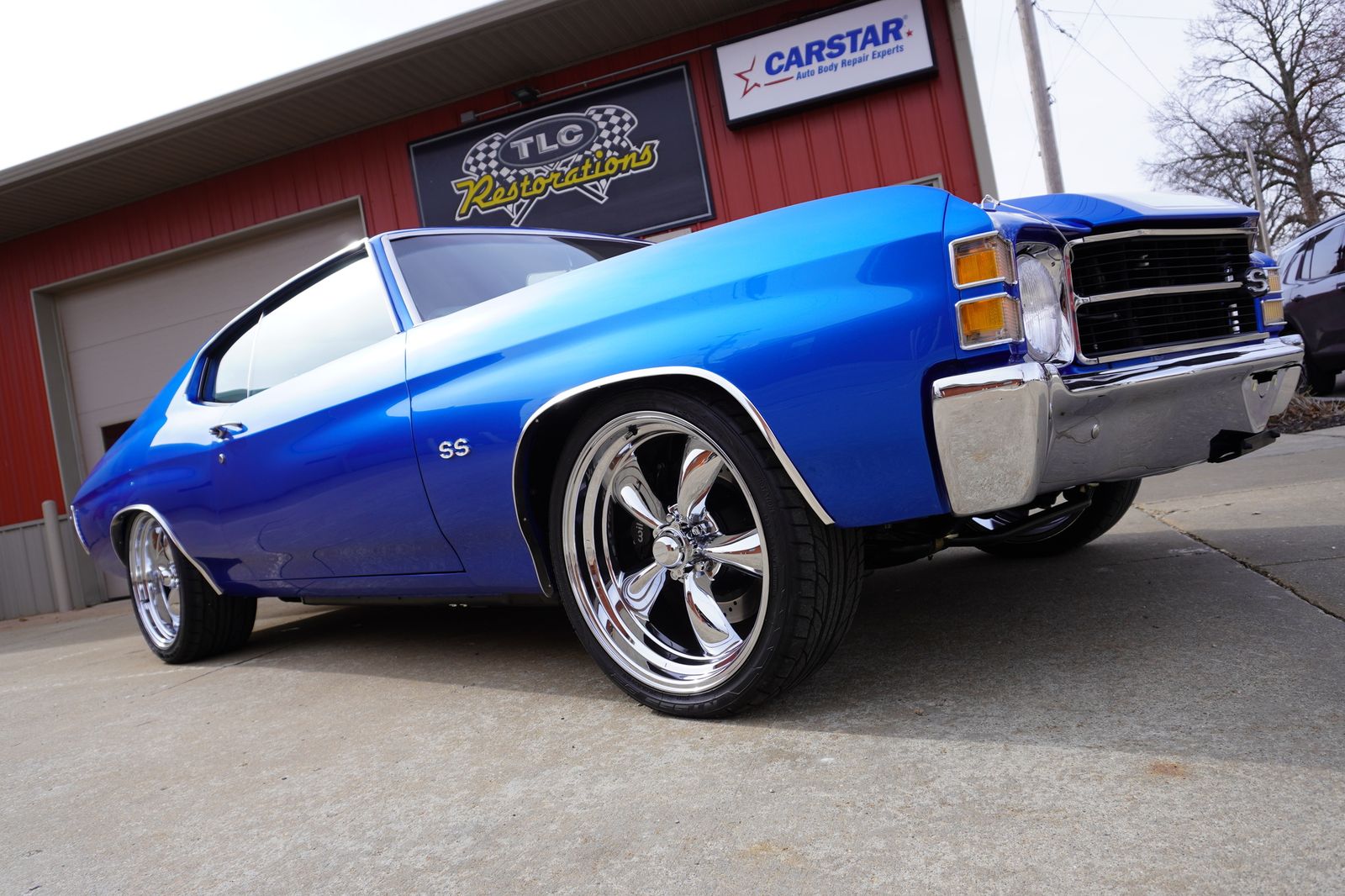 A restored blue Chevelle SS outside a restoration shop