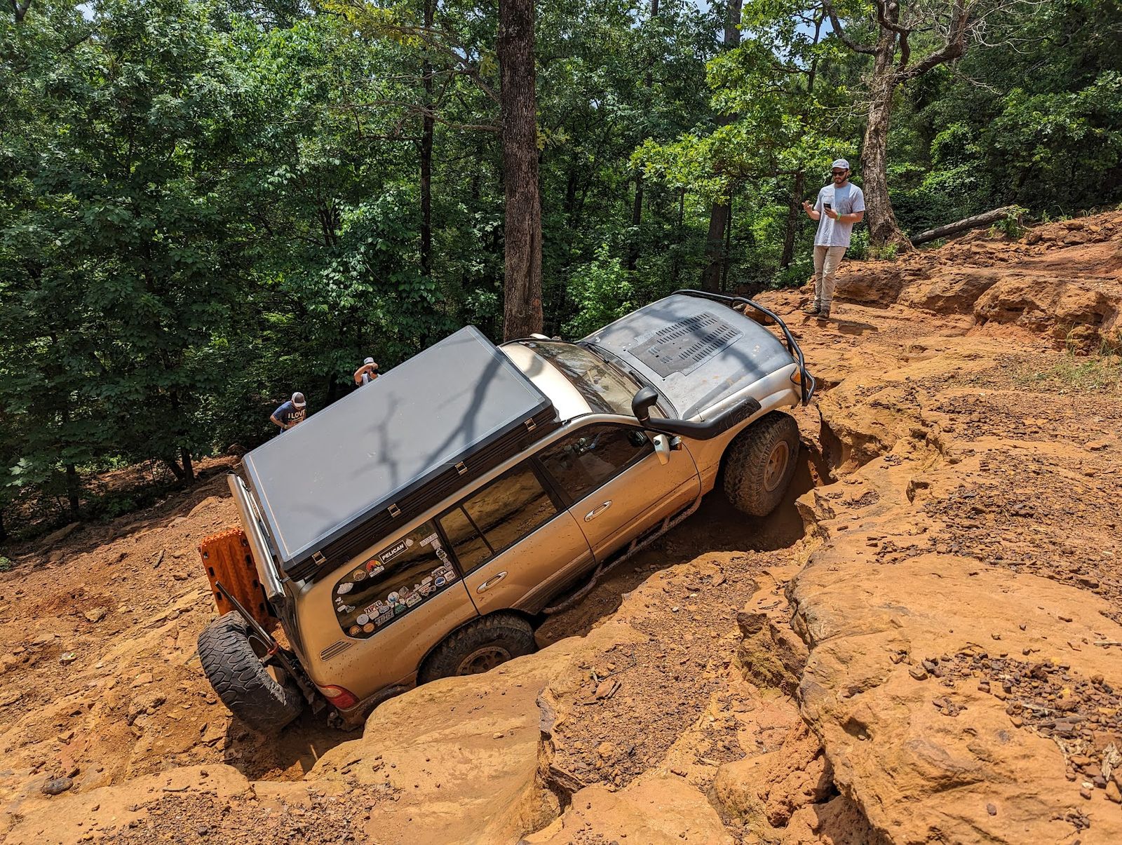 A built Land Cruiser crawling a rock ledge on a trail