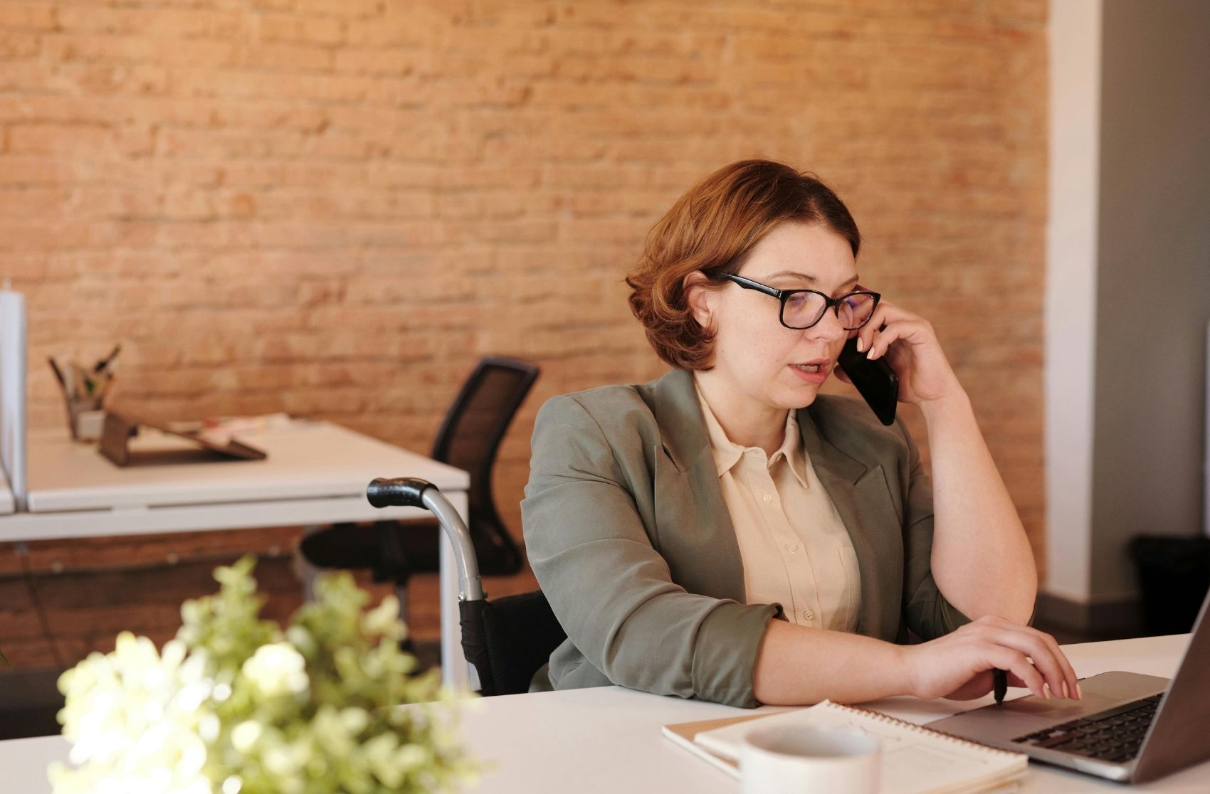 Woman Talking Through Smartphone While Using Laptop