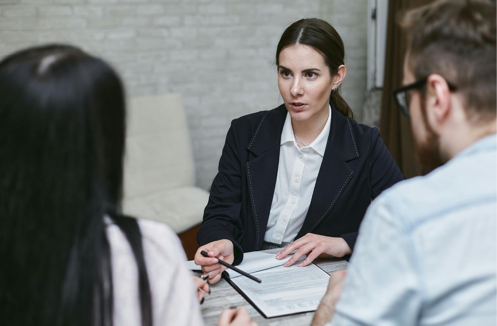 Woman in black blazer talking to a man and woman