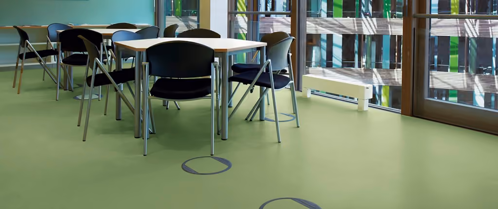 Groene rubbervloer in een ruimte met tafels en stoelen
