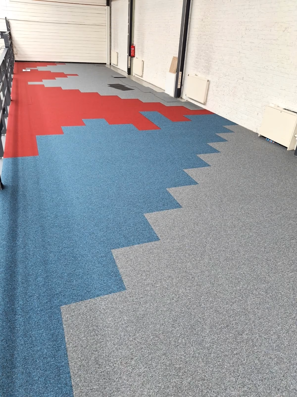 Tapijttegels in rood, blauw en grijs met een geometrisch patroon