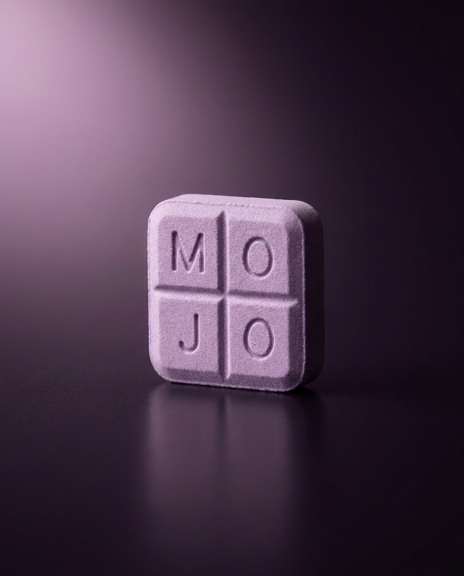 A lavender Mint Mojo troche embossed MOJO, lit against a deep violet background