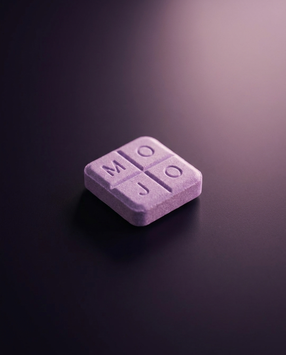A lavender Mint Mojo troche embossed MOJO, standing on dark slate