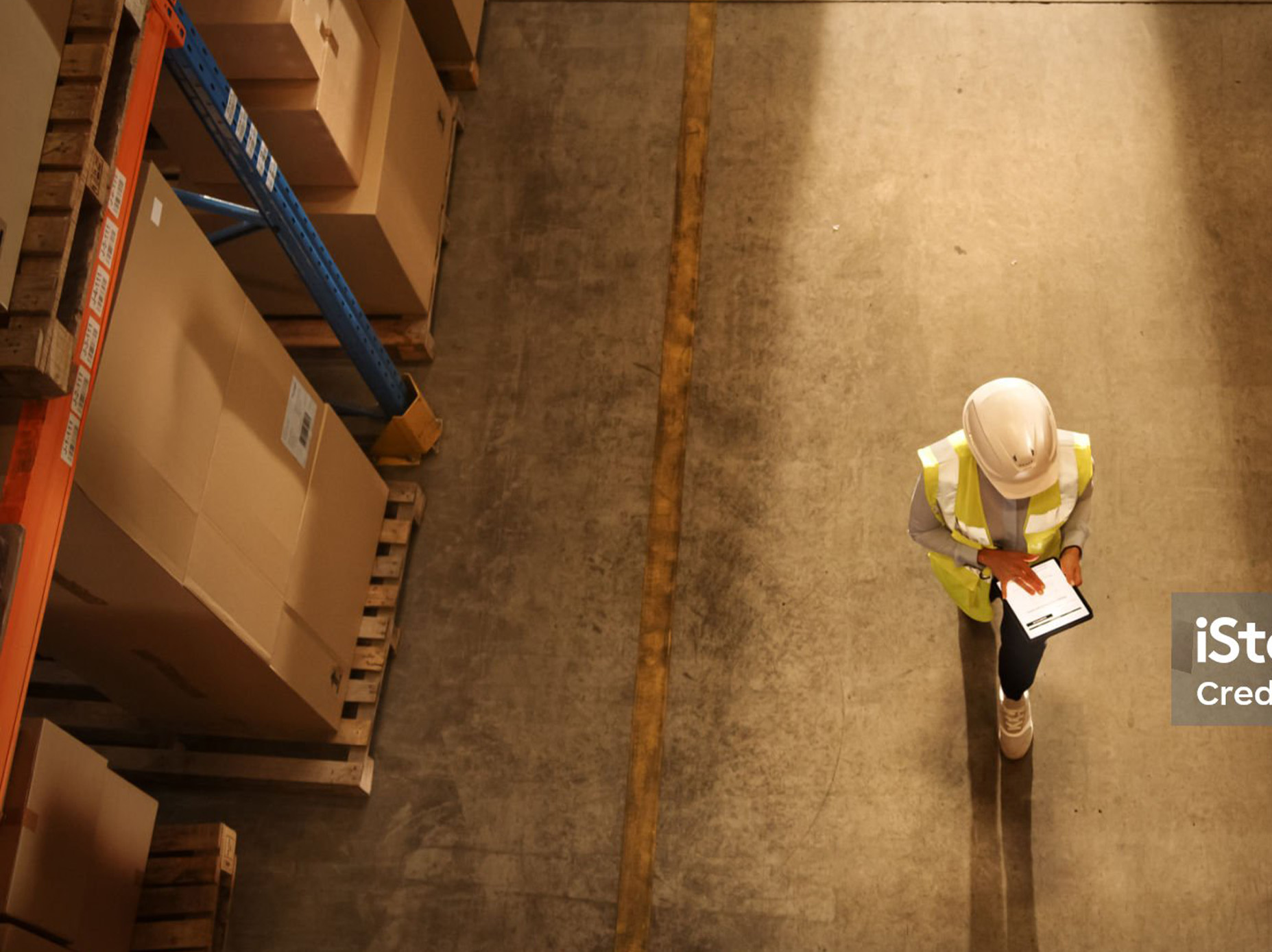 Procurement worker reviewing orders on a tablet in a warehouse aisle