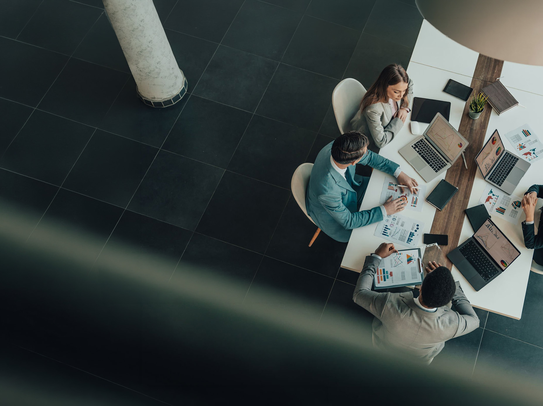 Overhead view of a team reviewing financial charts and documents at a boardroom table