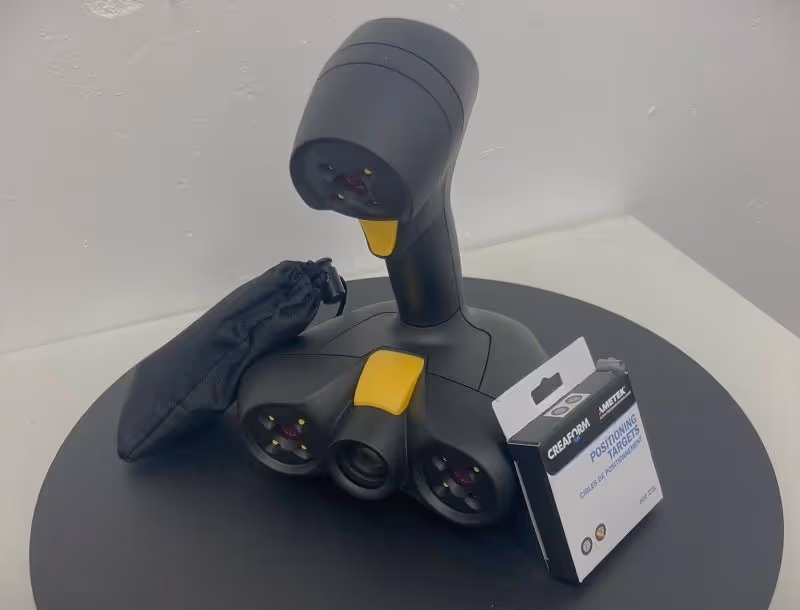 A handheld 3D scanner on a mobile turntable. The scanner is black.