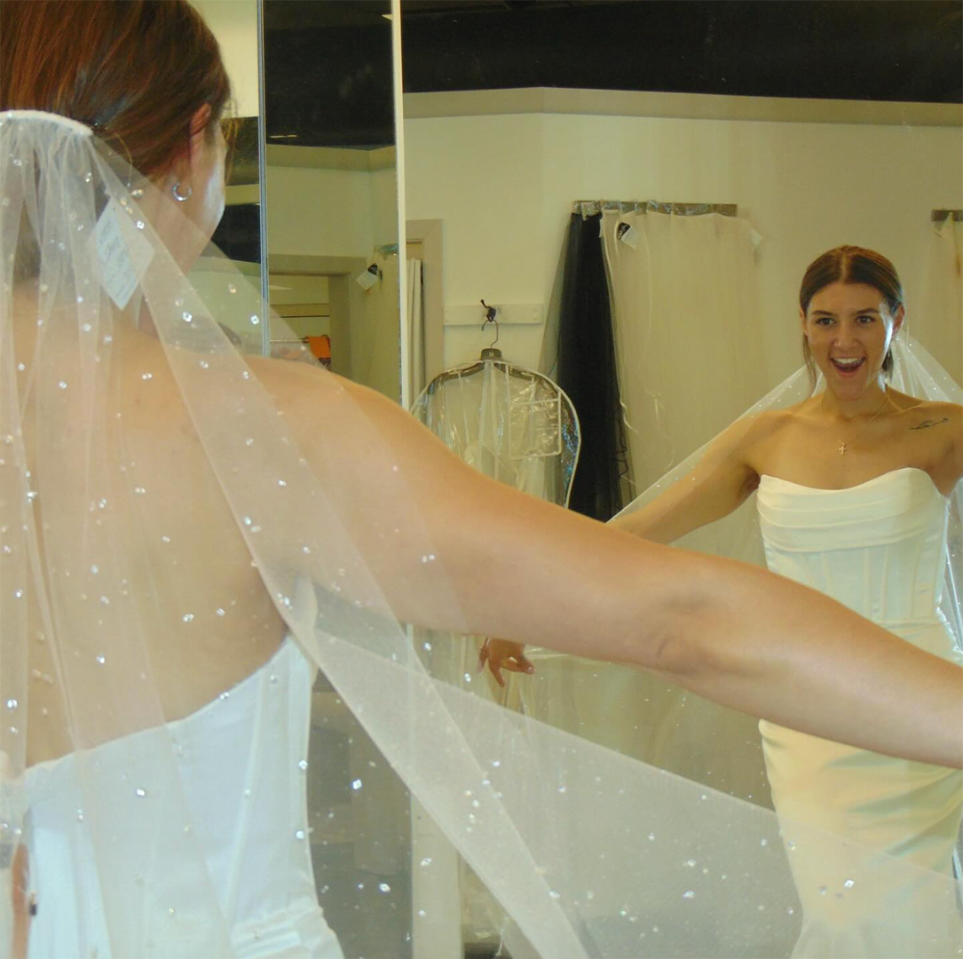 bride to be looking at wedding dress in mirror