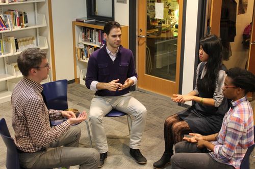 A group of people engaging in a discussion in a workshop or meeting room setting.