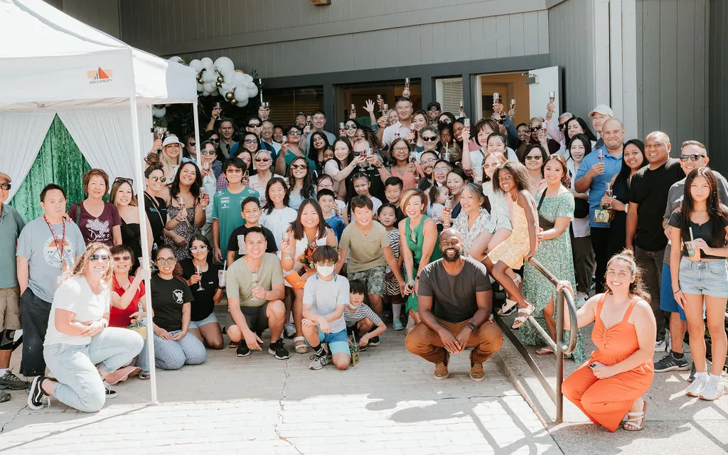Group of attendees posing in front of a new business during its grand opening coordinated by Stellify Events.