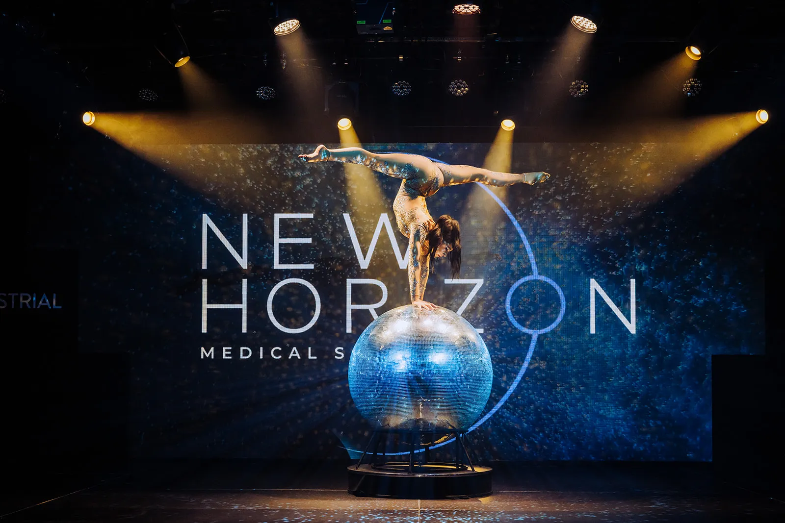 Acrobatic performer doing a hand stand on a disco ball at an event planned and directed by Stellify Events.