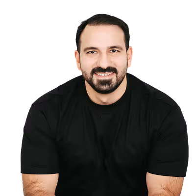 Smiling man with short dark hair and beard wearing a black t-shirt against a white background.
