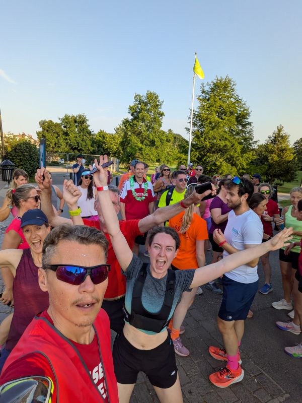 A selfie of cheering runners with their arms in the air, gathered in a park before the Rave Run