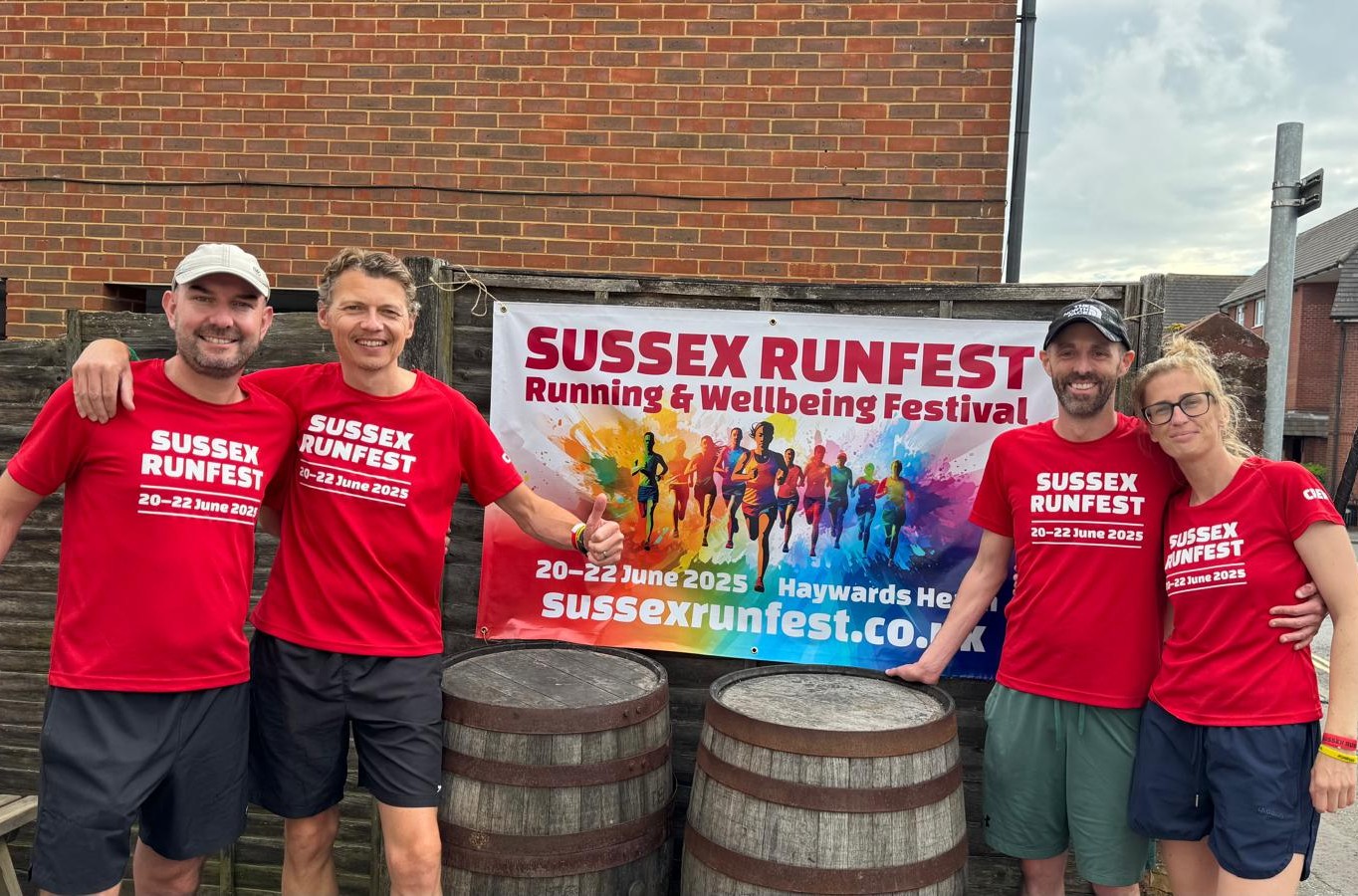 The RunFest core team, Tom, Ben, Clare and Jon, in red RunFest 2025 t-shirts beside the first festival’s banner