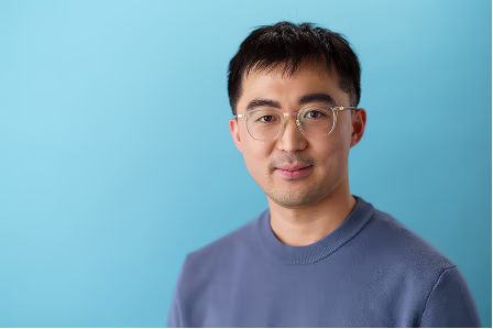 Notable team headshot of a man with glasses against a blue background