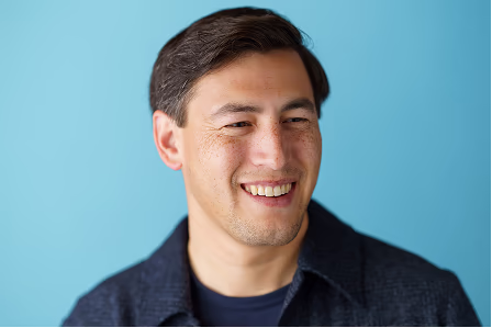 Notable team headshot of a smiling man against a blue background