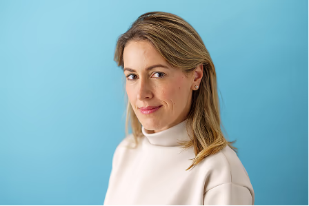 Notable team headshot of a woman in a white top against a blue background