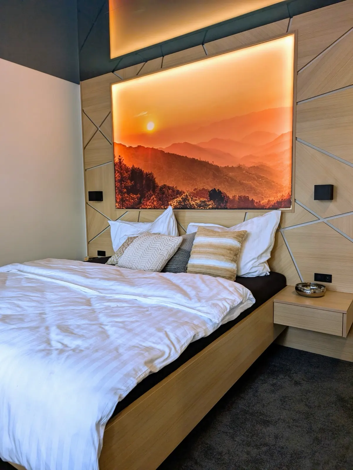 Schlafzimmer mit Doppelbett in Eiche, verkleideter Kopfwand und indirektem Licht