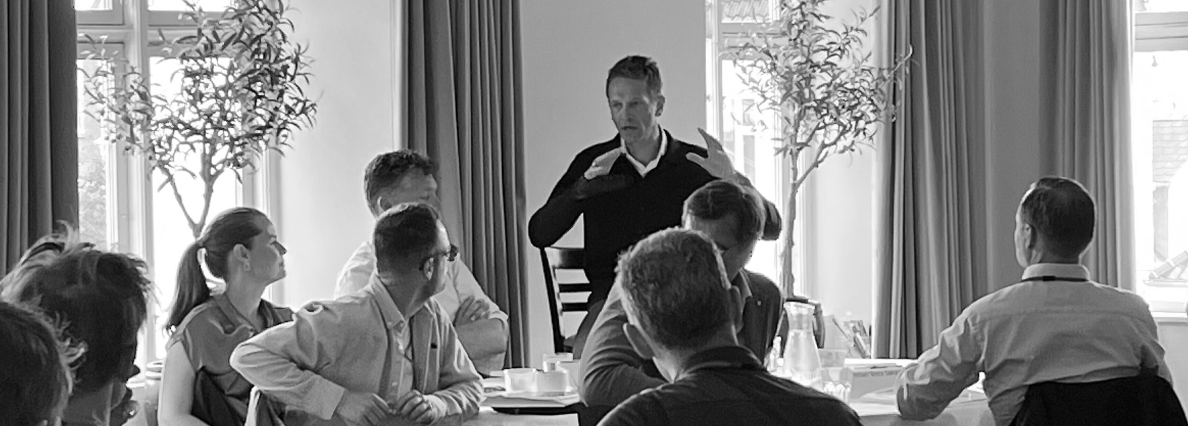 A picture of Tue Mantoni delivering a speech to the crowd in a conference room.