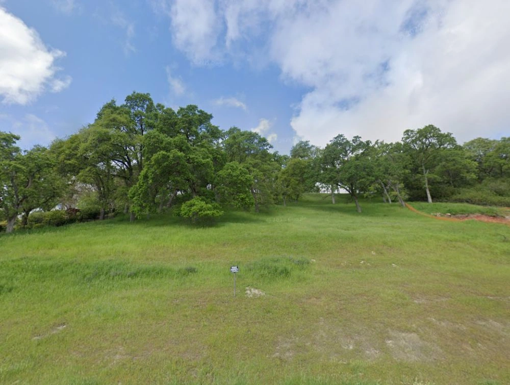 Global Arch Construction site photo of Rocklin lot with grassy field, oak trees, and open blue sky