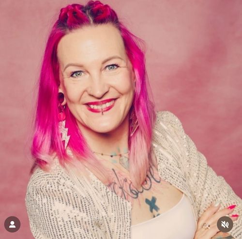 Lächelnde Frau mit pinken, schulterlangen Haaren