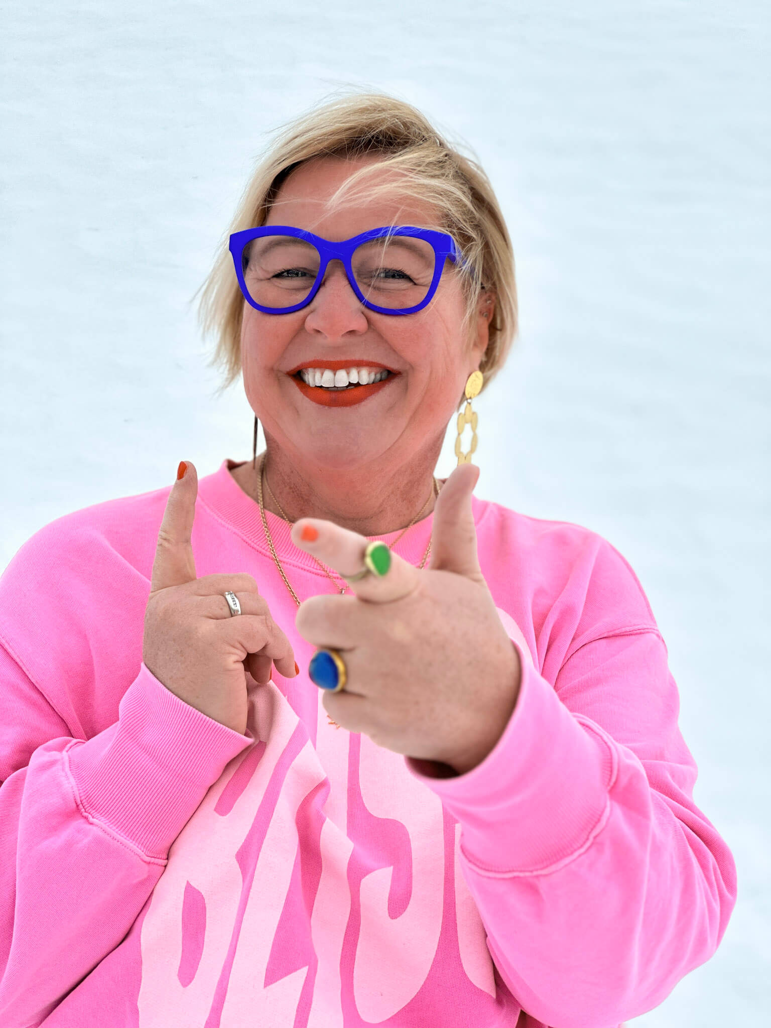 Lachende Frau mit blauer Brille und pinkem Pullover