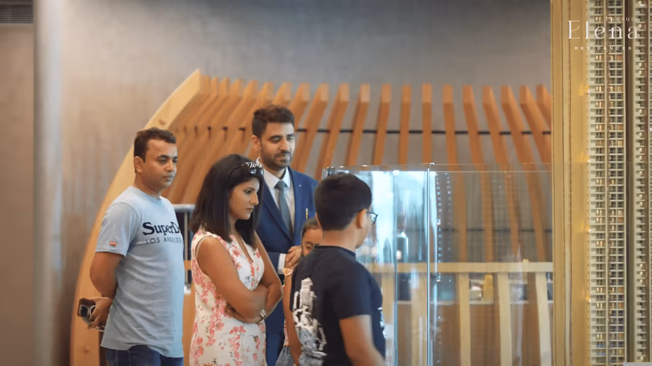 A group of people attentively looking at a building model inside a modern room with wooden architectural details.