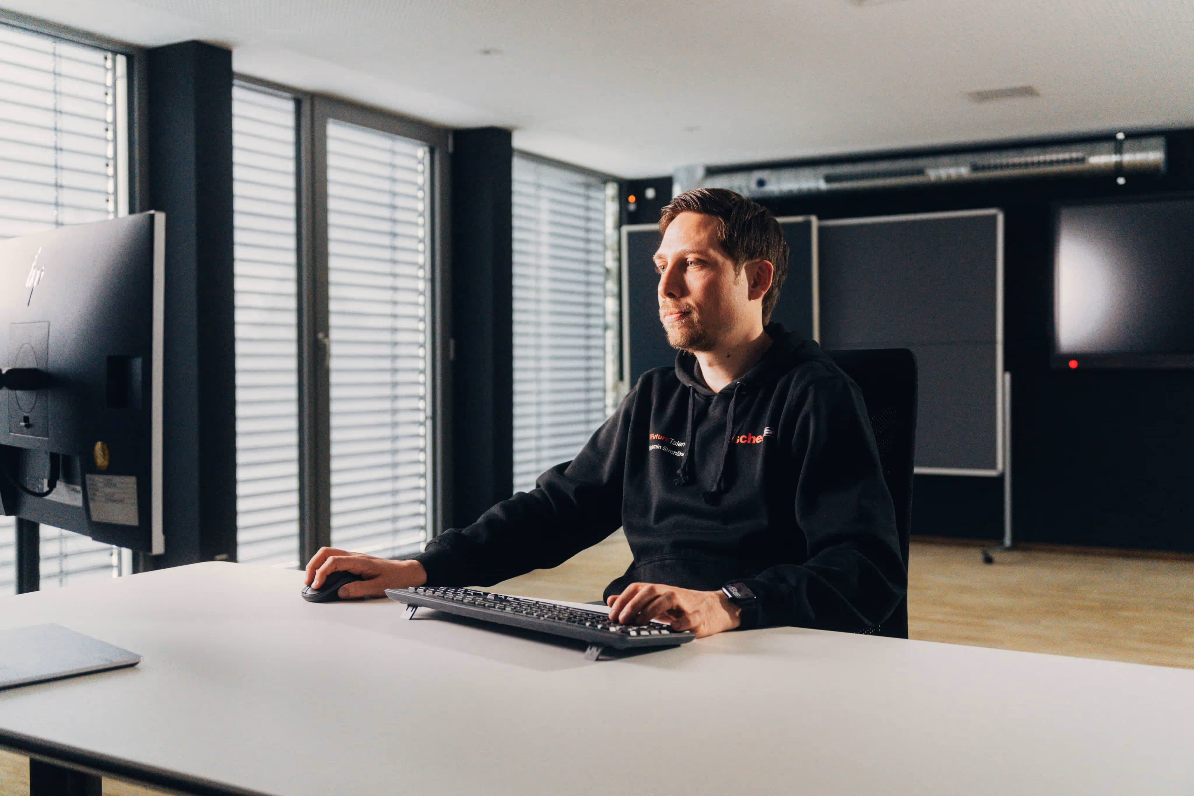 Ein Ausbilder sitzt am Schreibtisch und nutzt simpleclub zur digitalen Ausbildung seiner Azubis