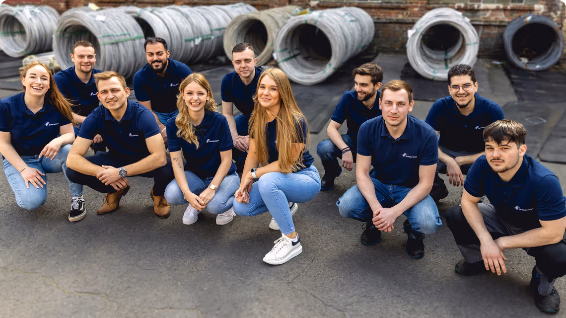 Mitarbeiterin der Deutschen Nickel GmbH steht vor weißem Hintergrund, trägt einen blauen Blazer und lächelt in die Kamera.