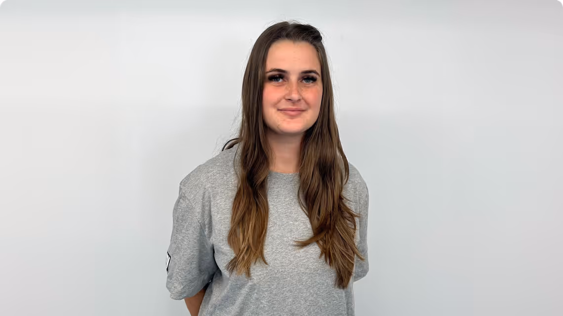 Auszubildende von BIW Bürger Industriewerk steht vor einer weißen Wand und lächelt in die Kamera.