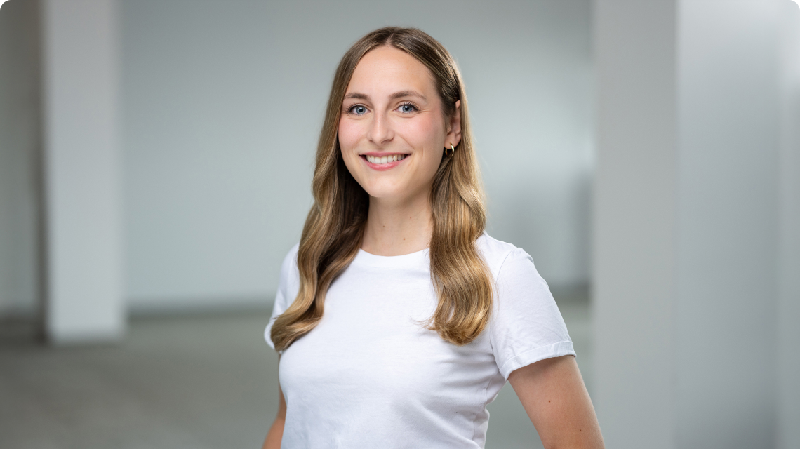 Mitarbeiterin von Deichmann lächelt in die Kamera, neutraler Hintergrund, Portraitaufnahme.