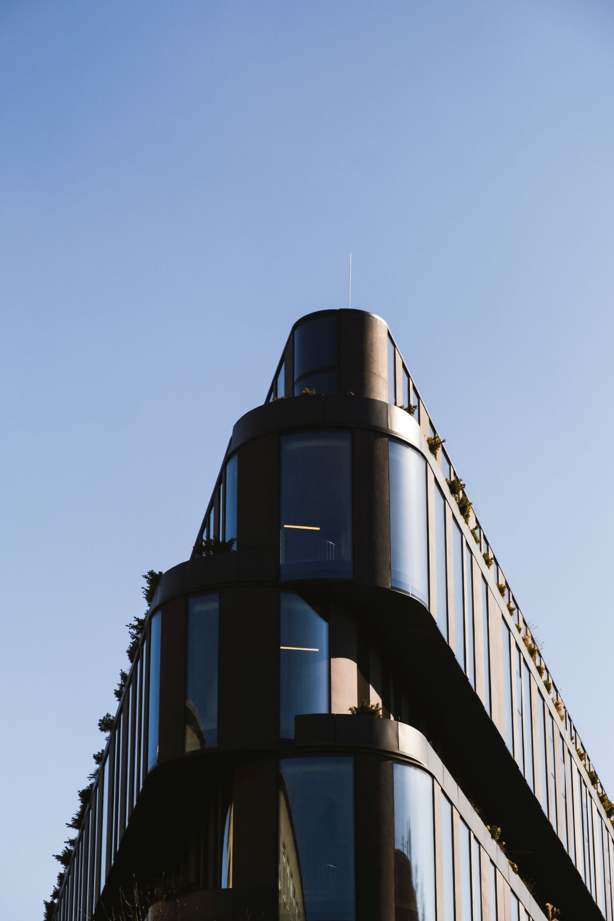 Ciemna elewacja Nobu Hotel Warsaw z zakrzywionym narożnikiem na tle błękitnego nieba.