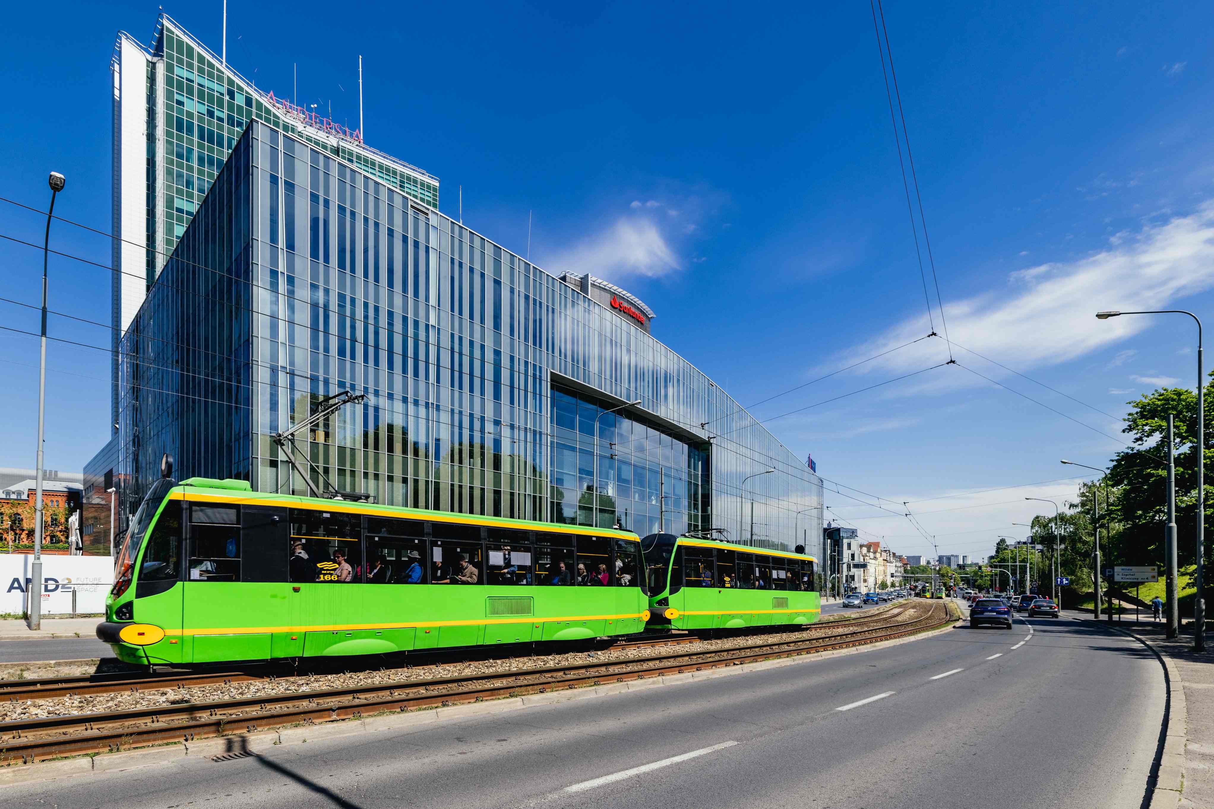 Nowoczesny przeszklony biurowiec Andersia Business Centre w Poznaniu widziany z poziomu ulicy z tramwajem