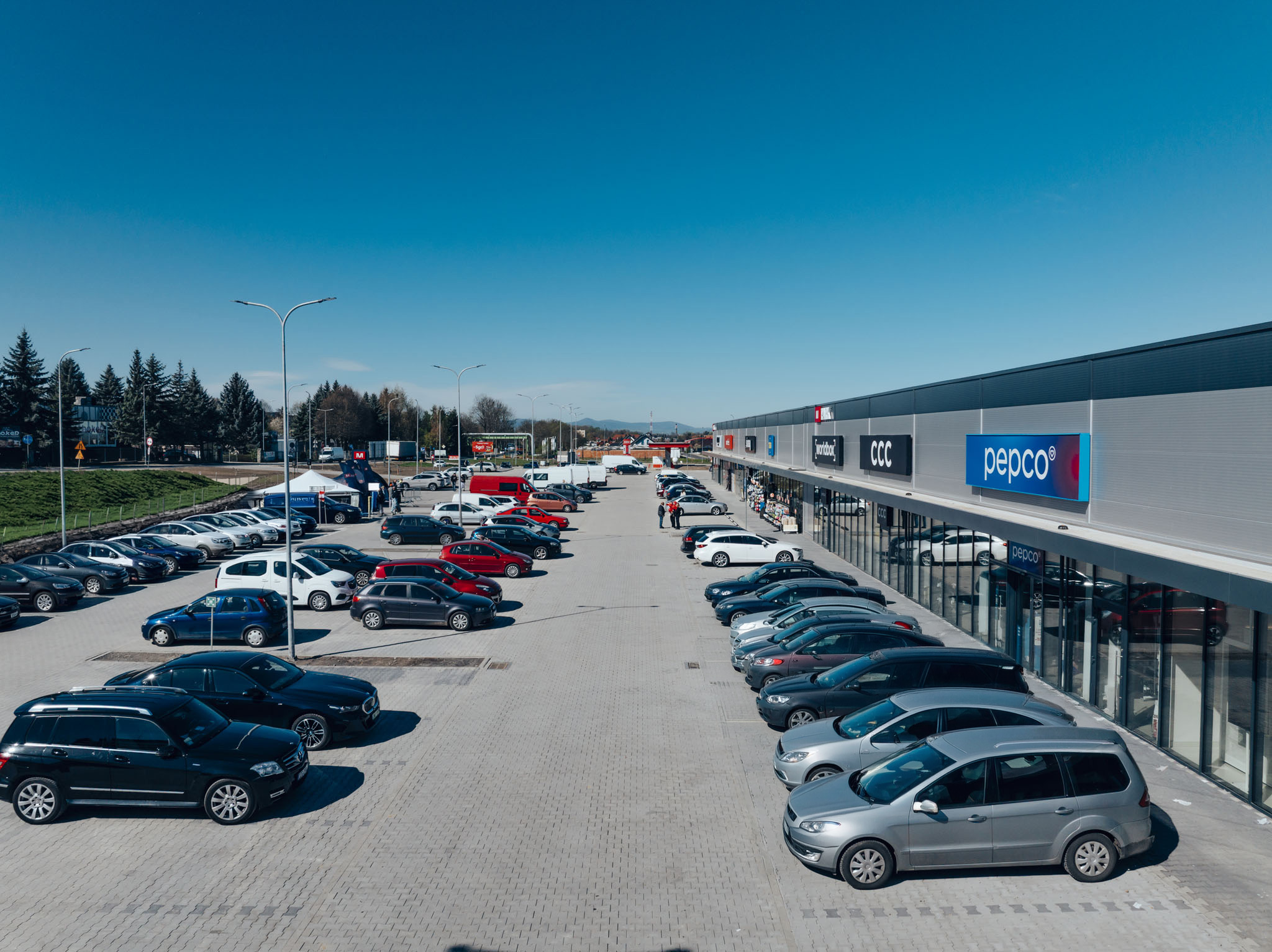 Szeroka panorama parkingu przed parkiem handlowym M Park w Bogatyni ze sklepem Pepco na pierwszym planie