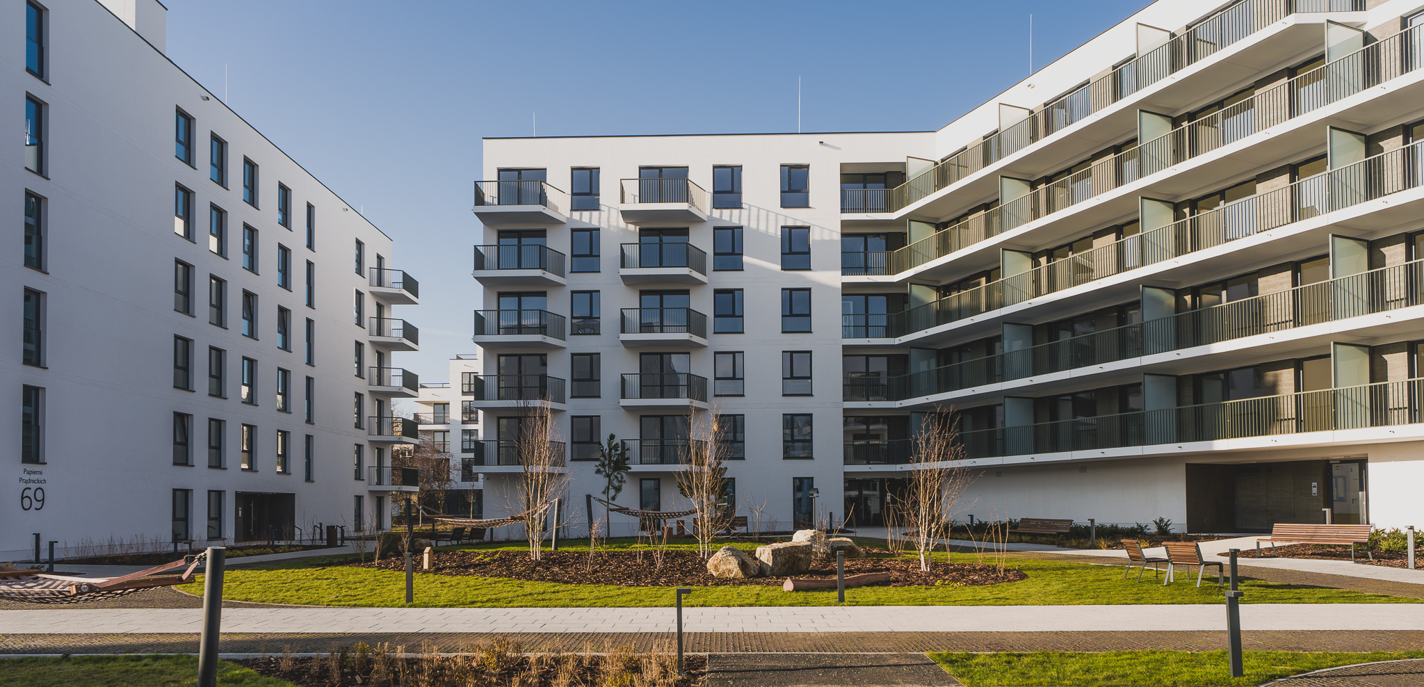 Tarasy zielone i schody terenowe na osiedlu, łączące różne poziomy terenu z roślinnością.