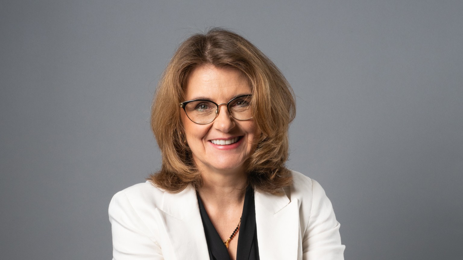 Agnieszka Jagiełka to młoda kobieta z uśmiechem, stojąca na tle logo firmy ISS.