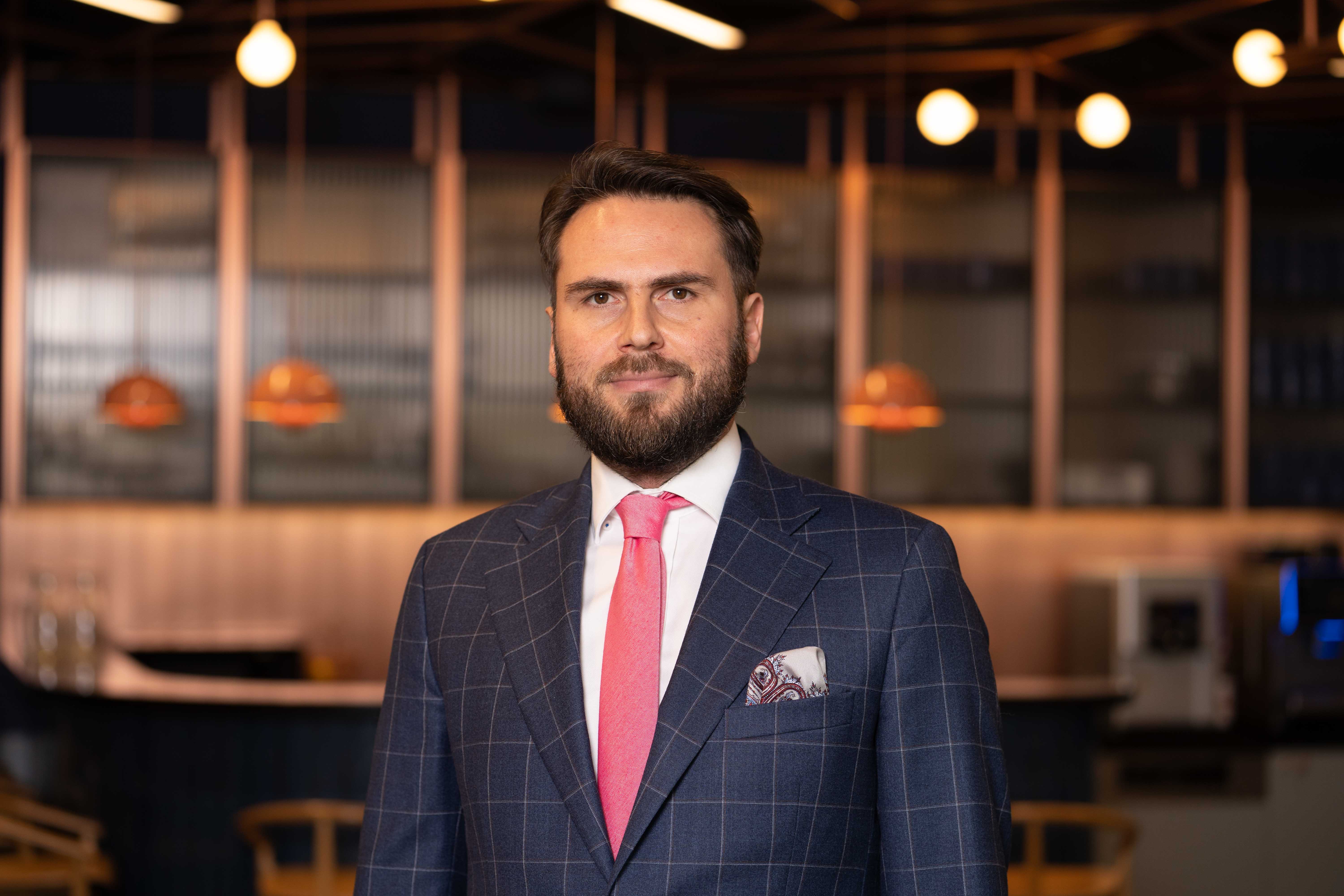 Dariusz Chrzanowski, dyrektor ds. strategii kontraktacji energii w Colliers, uśmiecha się na tle białego lub jasnego tła.