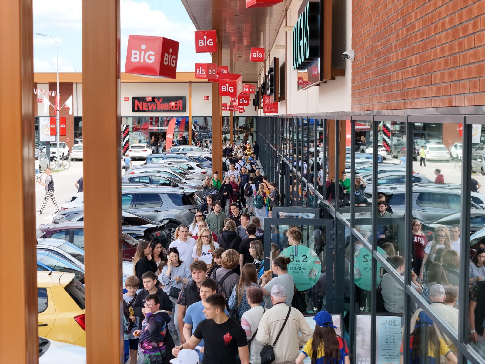 Budynek centrum handlowego BIG Dzierżoniów widziany z zewnątrz z rozległym parkingiem przed wejściem dla klientów.