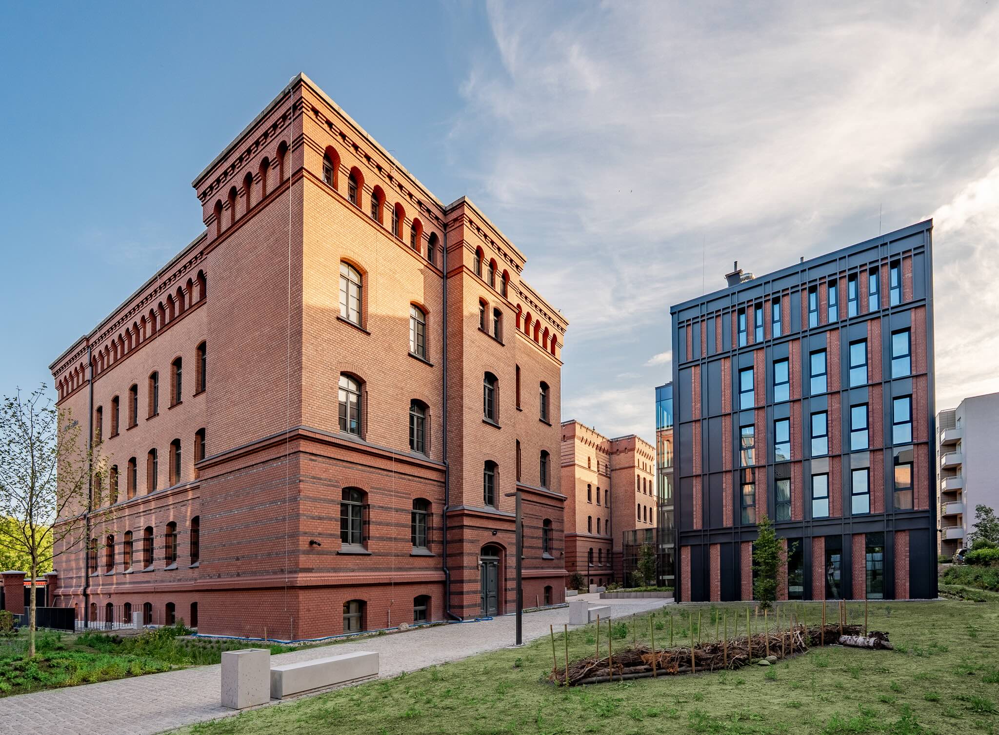 Zabytkowy gmach z czerwonej cegły sąsiaduje z nowoczesnym, biurowym budynkiem.