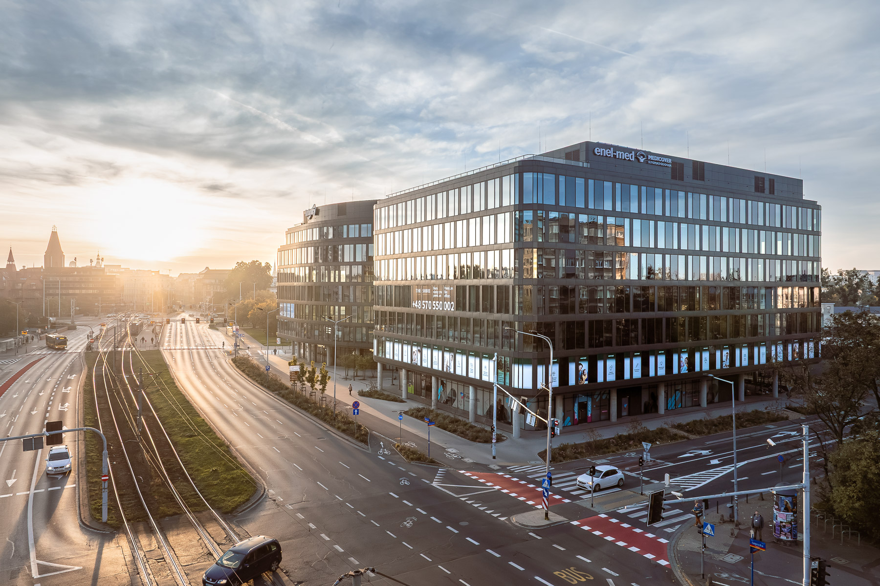 Współczesny, wielokondygnacyjny biurowiec o przeszklonej elewacji i zaokrąglonych narożnikach dominuje na skrzyżowaniu miejskich arterii z torowiskiem tramwajowym.