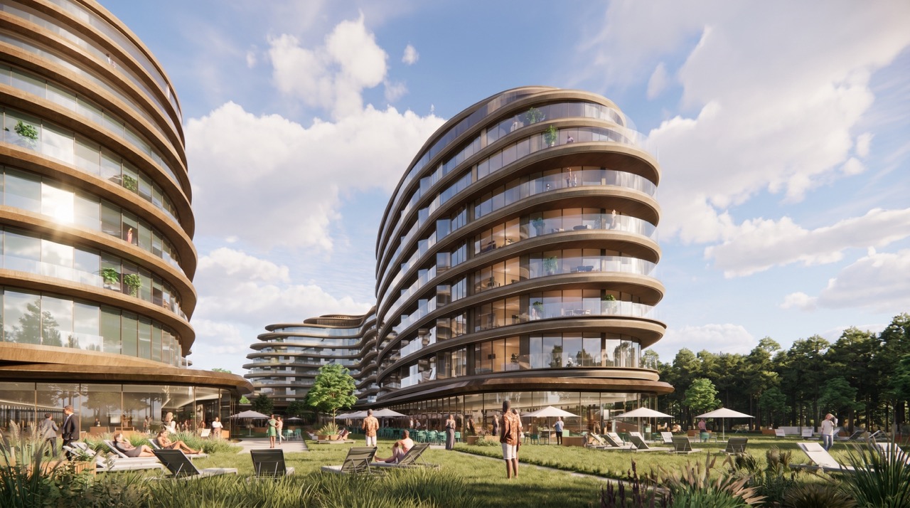 Nowoczesny kompleks apartamentowy o obłych kształtach i przeszklonych kondygnacjach z piaskowymi elementami elewacji i balkonami. Przed obiektem zadbany trawnik z leżakami, stolikami pod parasolami. W tle las iglasty.