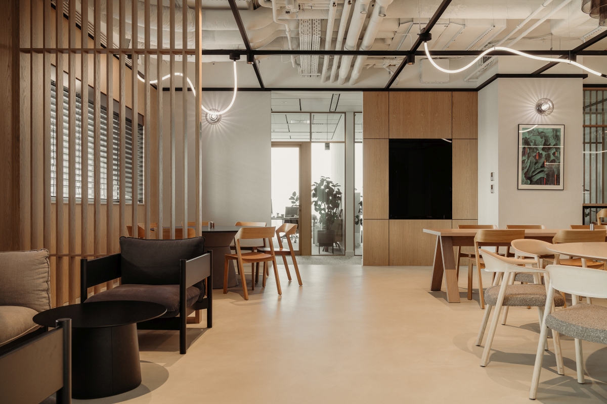 Nowoczesne wnętrze biurowe w stylu industrialnym z drewnianymi panelami, otwartym sufitem, czarnymi fotelami i liniowymi lampami LED.
