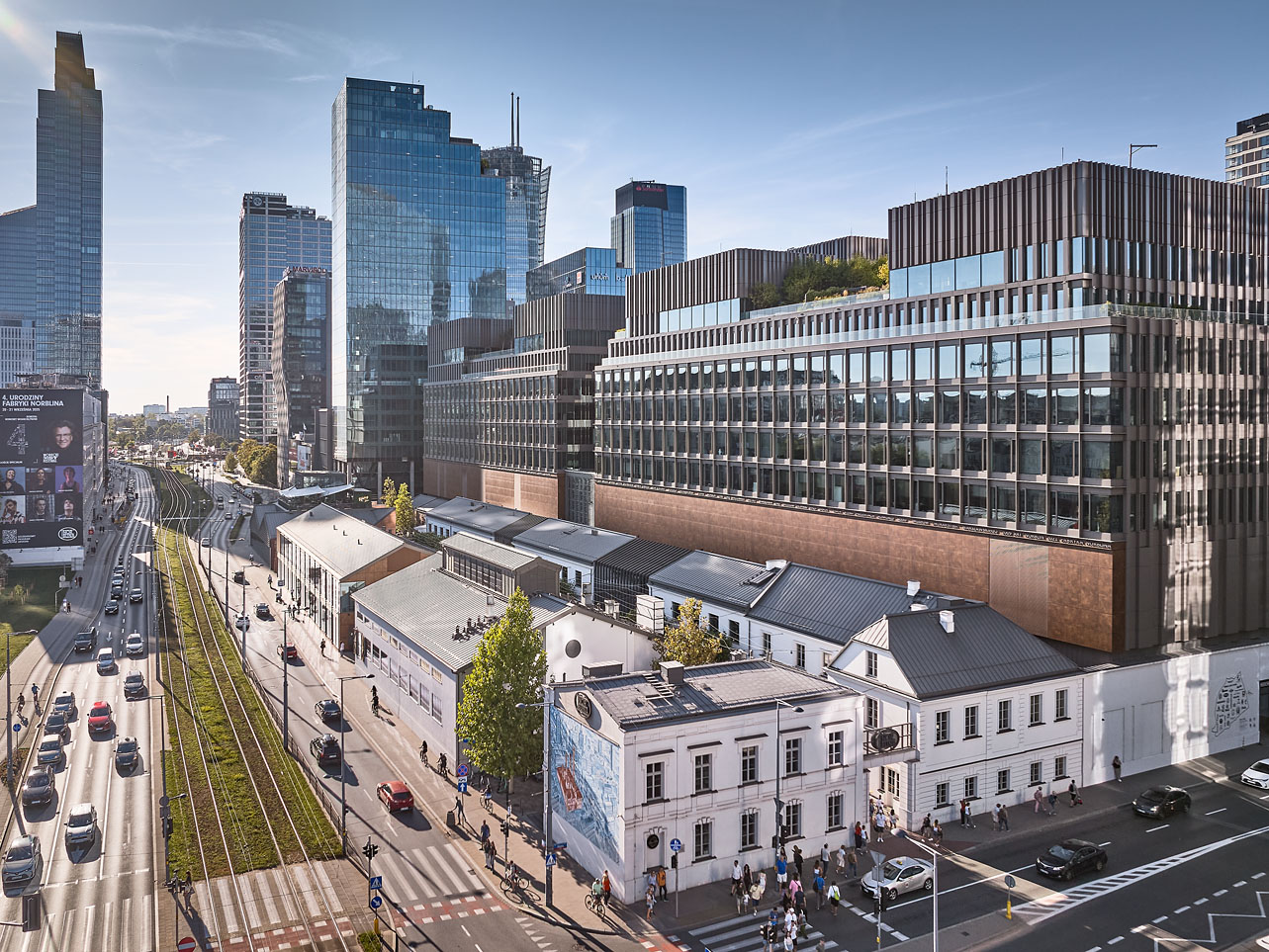Panorama wielkomiejskiej ulicy z niską, zabytkową zabudową i nowoczesnymi szklanymi wieżowcami