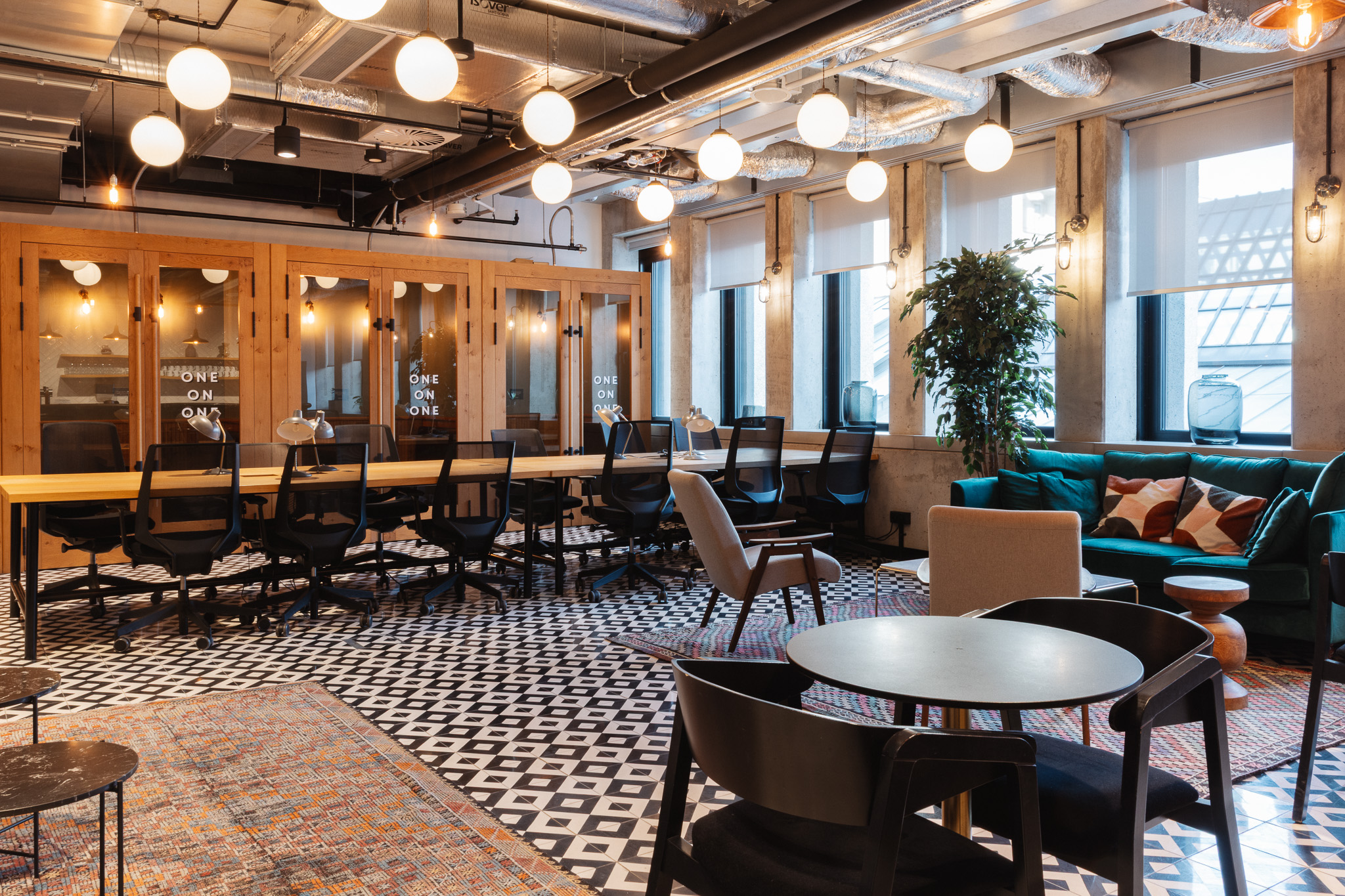 Nowoczesne wnętrze biurowe coworking łączy styl industrialny z elementami retro, z odsłoniętymi instalacjami i wzorzystą podłogą.