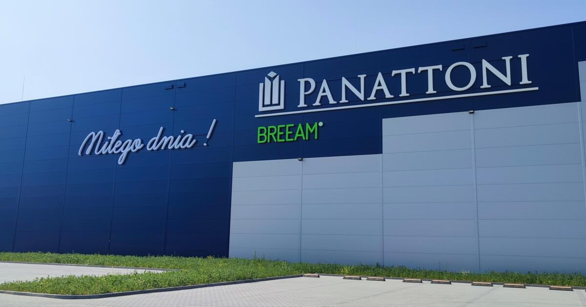 Elewacja hali magazynowej z logotypem Panattoni, zielonym napisem BREEAM oraz parkingiem z kostki brukowej.