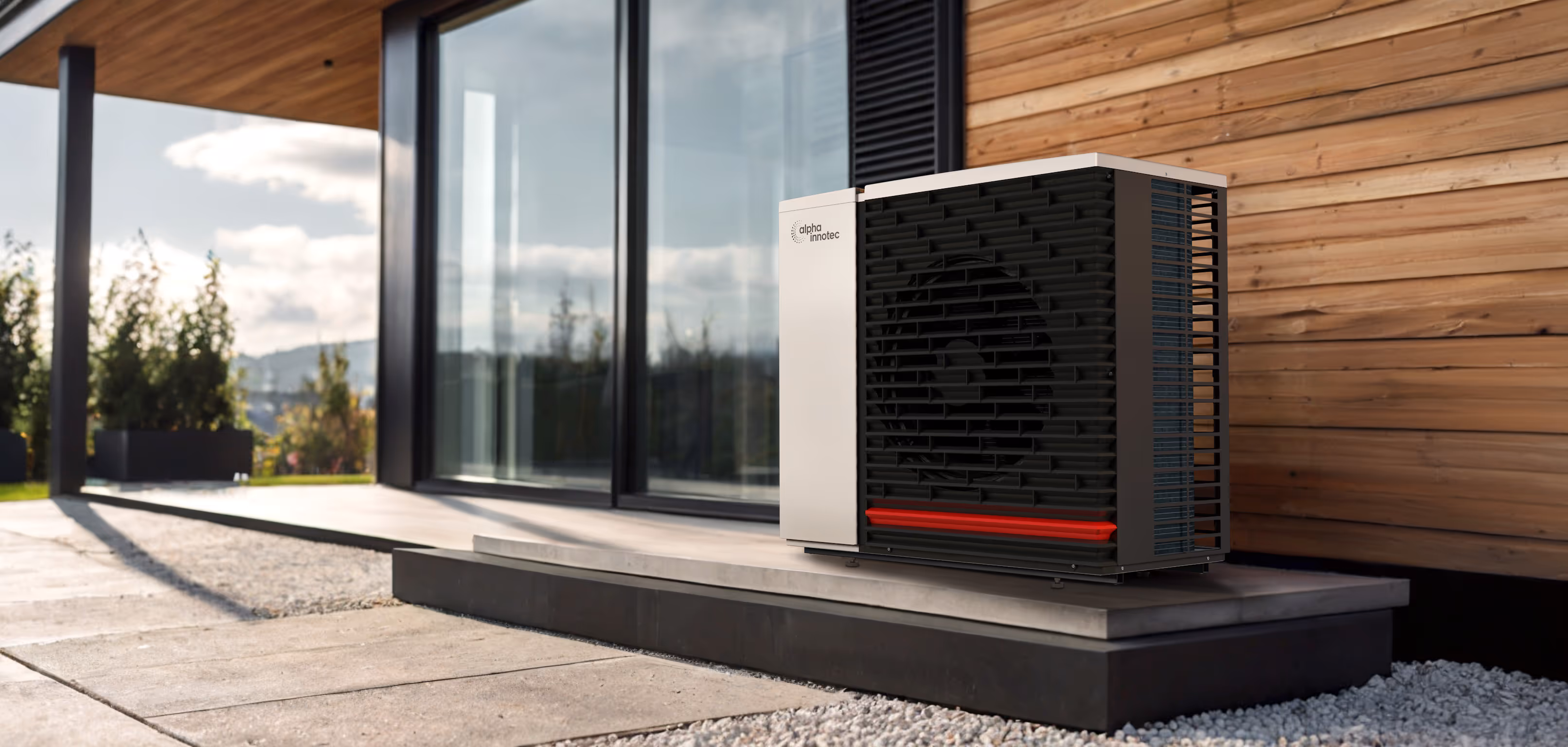 Alpha Innotec Hybrox Wärmepumpe vor modernem Haus mit Holzwand