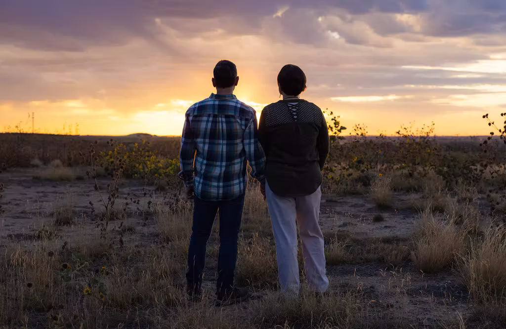 A couple watching the sunset while holding hands