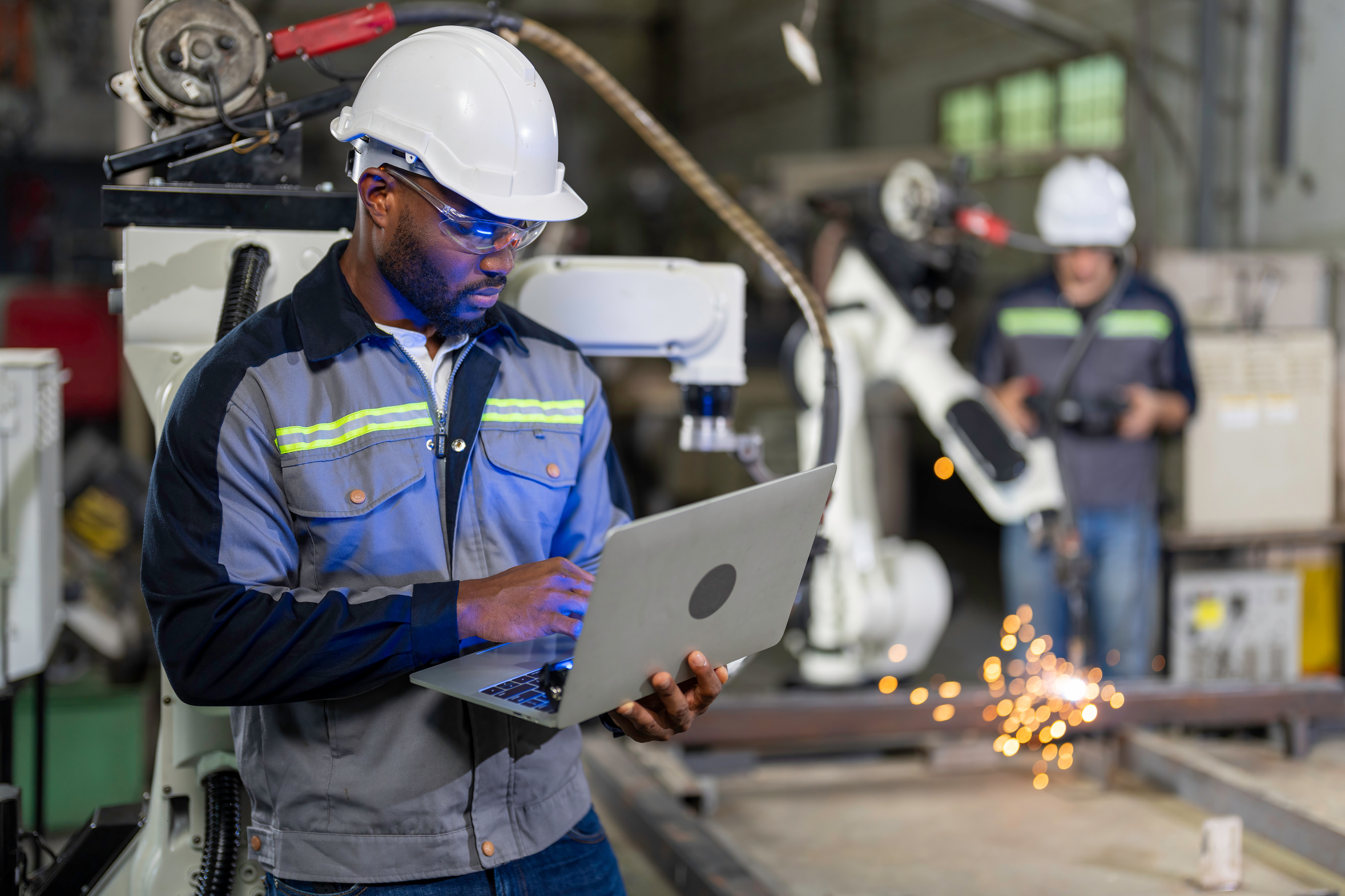 Engineer maintaining a robotic welding machine in a factory