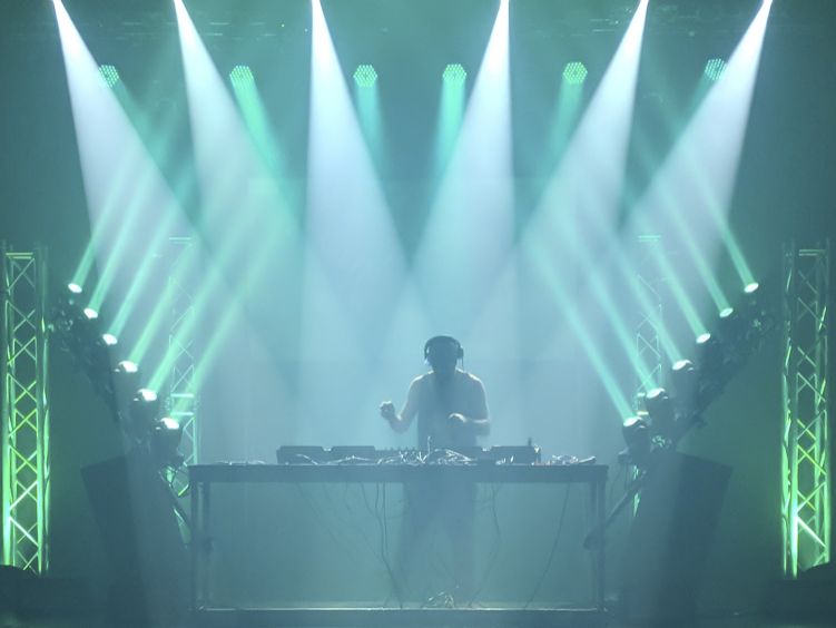 Live DJ set with professional stage lighting design including moving head lights and LED truss towers from Contak AV event production services