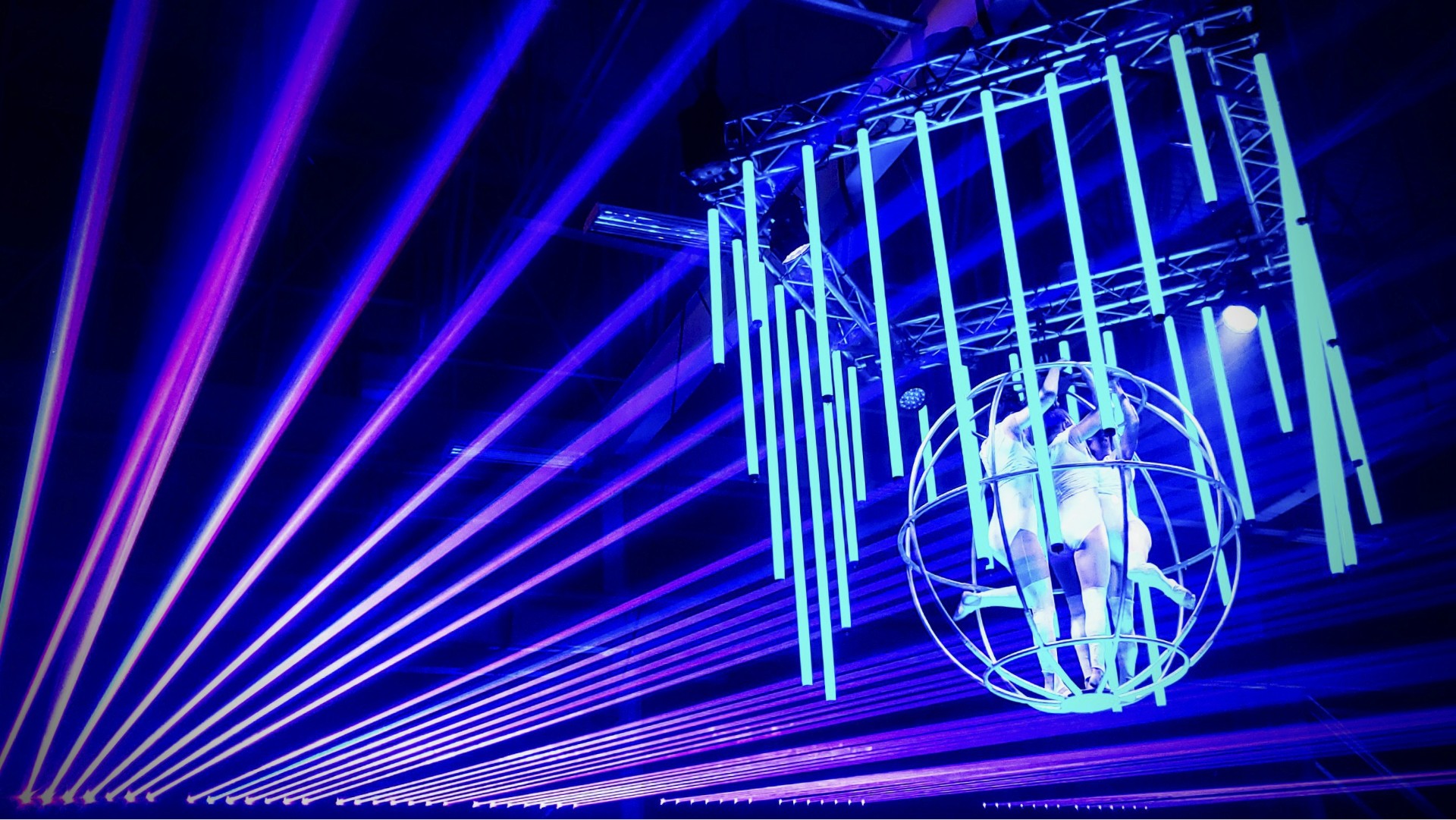 Contak AV stage design with custom rigging, truss-mounted performers, and vibrant purple and blue lighting for a luxury experiential event in Montreal.